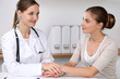 © rogerphoto - Doctor reassuring her female patient while  sitting at the desk. Medicine, help and health care concept