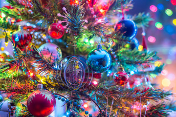 part of christmas tree, with colorful glass balls, small decorations and colorful light reflections