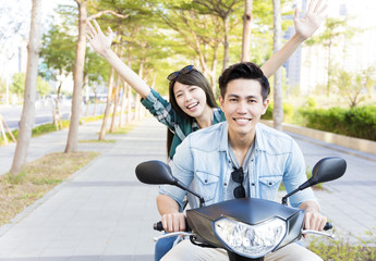 Wall Mural - happy young couple riding  scooter in town