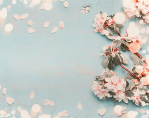 Pretty spring blossom on light blue background with bokeh, top view, pastel color, border