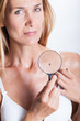© plprod - femme examinant avec une loupe un grain de beauté