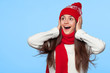 © nikolas_jkd - Happy surprised woman looking sideways in excitement. Christmas girl wearing knitted warm hat and mittens, isolated on blue background