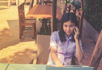 Young woman working with laptop and use smartphone at outdoor ca