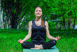 © Dimid - Beautiful young athlete sits in a lotus position on the mat in the nature. Healthy lifestyle.