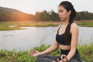 young woman meditates while practicing yoga outdoor in park,  re