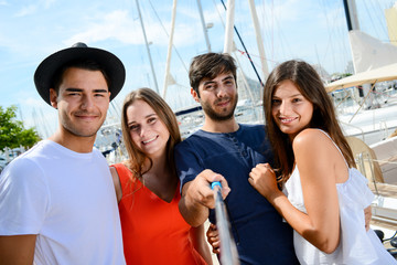 Wall Mural - group of four young people making selfie on the harbor of touristic resort