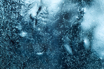 Frozen window with icy textured pattern, glass surface cracked ice macro view, soft focus shallow depth of field. cold weather concept