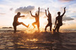 © Song_about_summer - group of happy friends having fun together on the beach at sunset, jumping and dancing with water splash in the sea, silhouettes of people