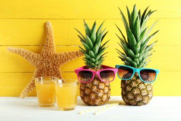 Poster - Ripe pineapples with glasses of juice on a white wooden table