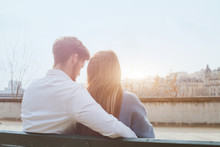 dating or first love, young couple sitting together on the bench, view from the back