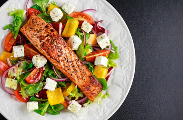 Fried Salmon steak with fresh vegetables salad, feta cheese. concept healthy food.