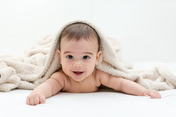 Cute baby boy in bed under a fluffy blanket