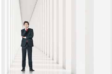 Young businessman in a suit is standing in a white corridor and thinking. Concept of management. 3d rendering. Mock up