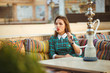 © vladstar - Beautiful young woman smokes a hookah in a cafe