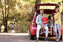 Family With Kids Sitting In Car Trunk