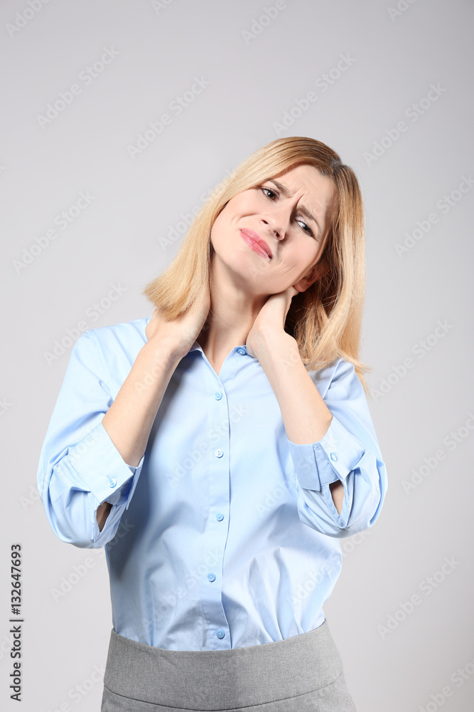 Young woman suffering from pain in neck on grey background