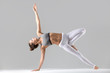 © fizkes - Young attractive woman practicing yoga, stretching in Side Plank exercise, Vasisthasana pose, working out wearing sportswear, white pants, indoor full length, isolated against grey studio background
