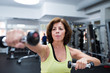 © Halfpoint - Senior woman in gym working out with weights.