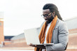 © santypan - Businessman using his laptop in the Street.