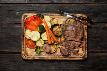 Poster - Grilled beef on the wooden board with a fork and a knife