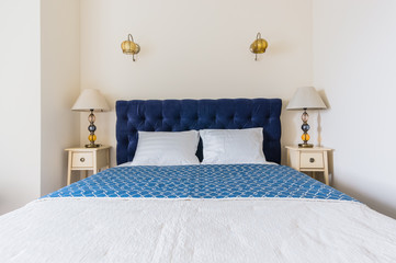 blue bed with soft headboard and bedside console with lamp