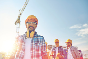 Canvas Print - group of smiling builders in hardhats outdoors