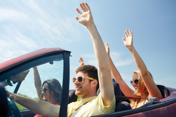 Wall Mural - happy friends driving in cabriolet car at country