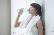 © PhotoAlto - Woman drinking bottled water in locker room