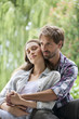 © PhotoAlto - Young couple embracing while sitting in the park