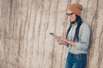 Poster - Modern pretty stylish woman in cap and glasses using tablet near