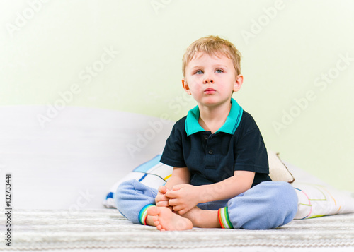 Skinny blond kid sitting on haunches on bed, placing pillows behind ...