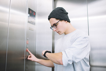 Young stylish guy standing in elevator