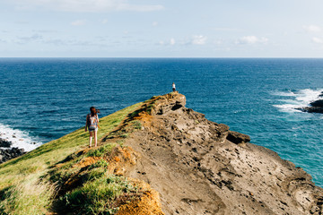 Girl walking on path on cliff by ocean