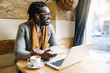 © santypan - Man with laptop sitting at table in cafe