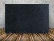 Blank long black fabric canvas frame leaning at concrete wall on