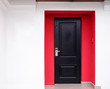 © maksim_e - The modern entrance door of dark color placed in a building facade which is painted in red and white colors