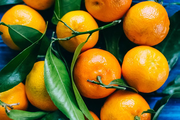 Tangerines with leaves on blue wooden table.