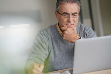 Wall Mural - Senior man at home connected on laptop computer