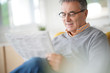 © goodluz - Smiling senior man with eyeglasses reading newspaper