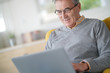 © goodluz - Senior man with eyeglasses connected on laptop at home