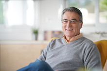 Smiling Senior Man With Eyeglasses Relaxing In Armchair