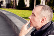 © Dragana Gordic - Sad Young Man sit on the Bench with Cigarette. portrait of a lonely man