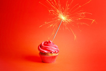 Wall Mural - Fresh tasty cupcake with sparkler on red background