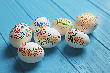 Wall Mural - Beautiful Easter eggs with floral ornament on blue wooden background