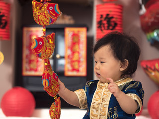 Asian baby girl playing with Chinese new year greeting decoratio