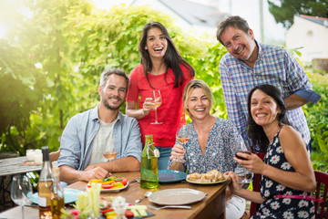 Wall Mural - Group of friends gathered around a table on a summer terrace