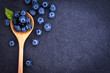  fresh picked blueberries in wooden spoon on black stone 