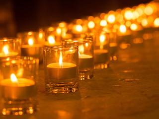 Golden light of candle flame in glass. Christmas candles burning at night. (selective focus)