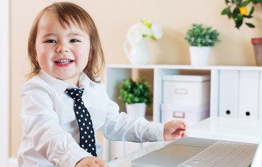 Wall Mural - Happy toddler girl smiling while using a laptop