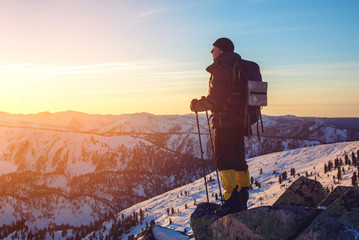 man hikers standing on snowy mountain peak at sunset